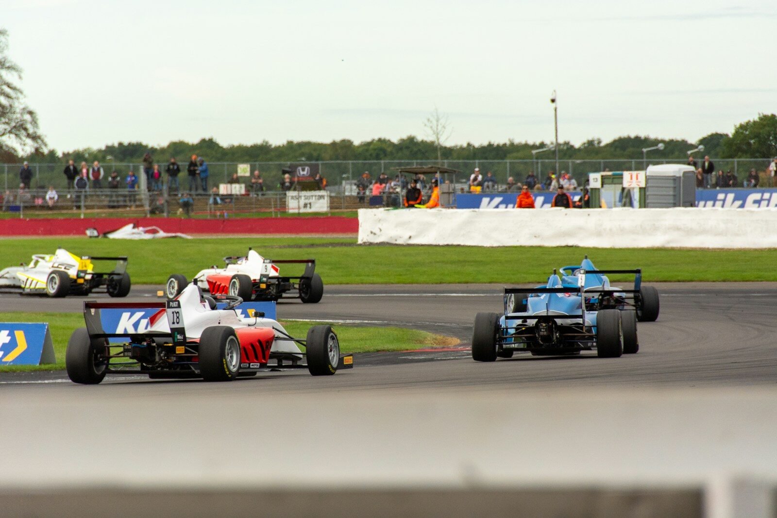 a group of racing cars driving down a race track